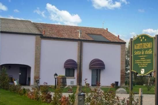 La facciata del casale, con le tende ad arco e l’insegna di legno all’ingresso